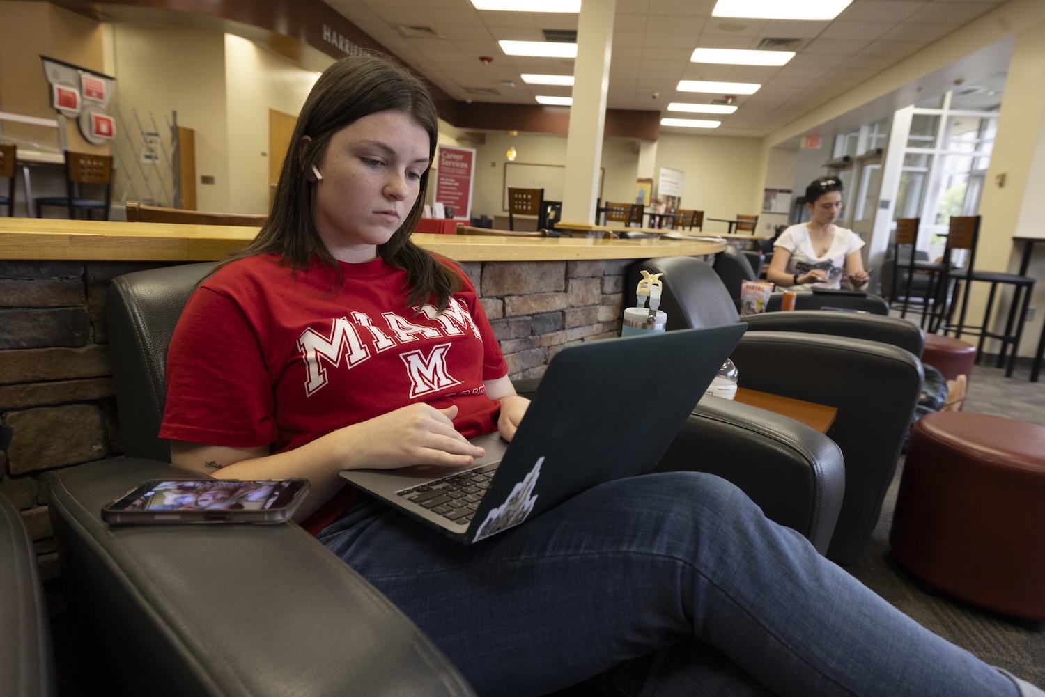 Student sitting in the Hamilton campus lounge using working on her laptop