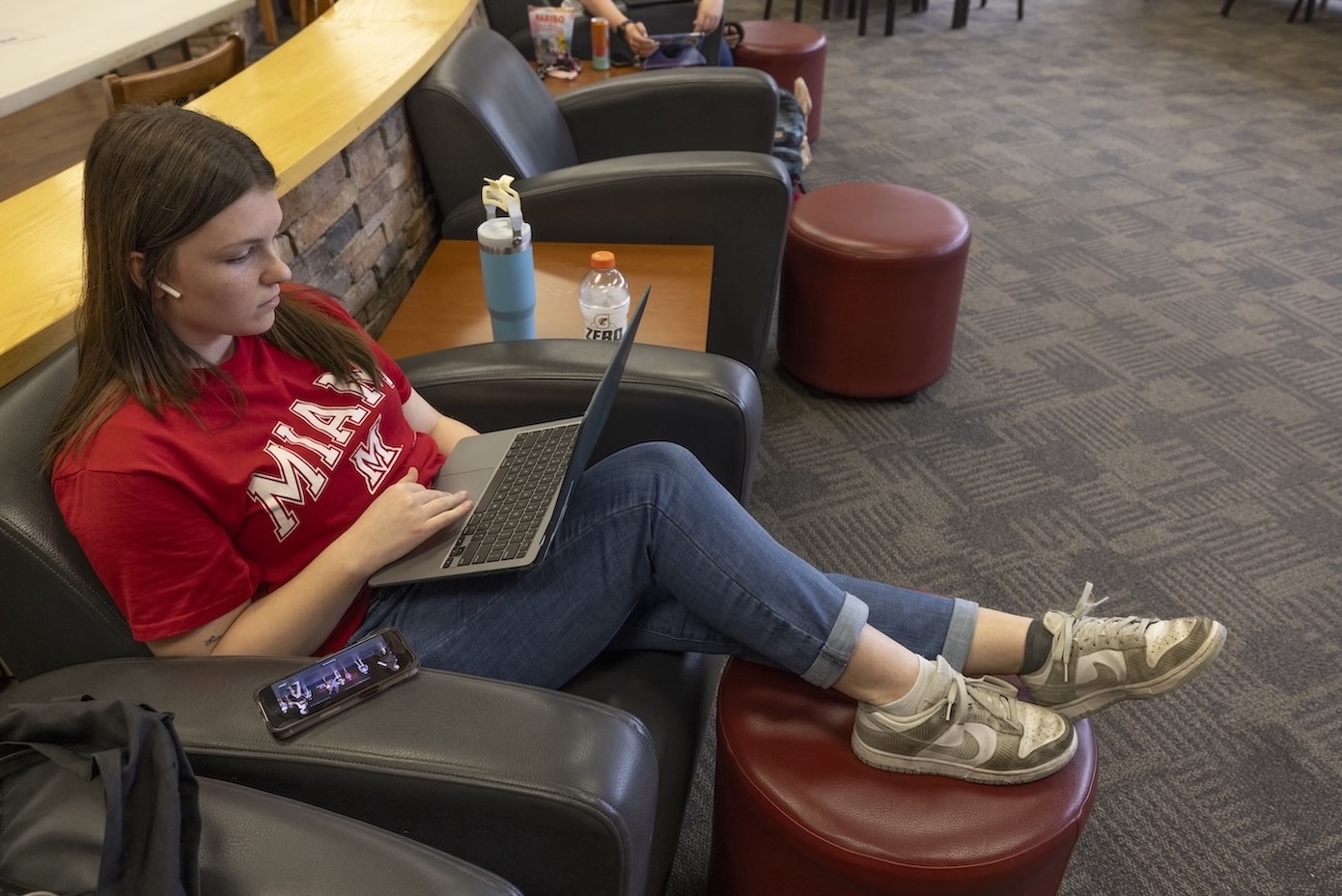 A female student sitting in a lounge chair working on her laptop
