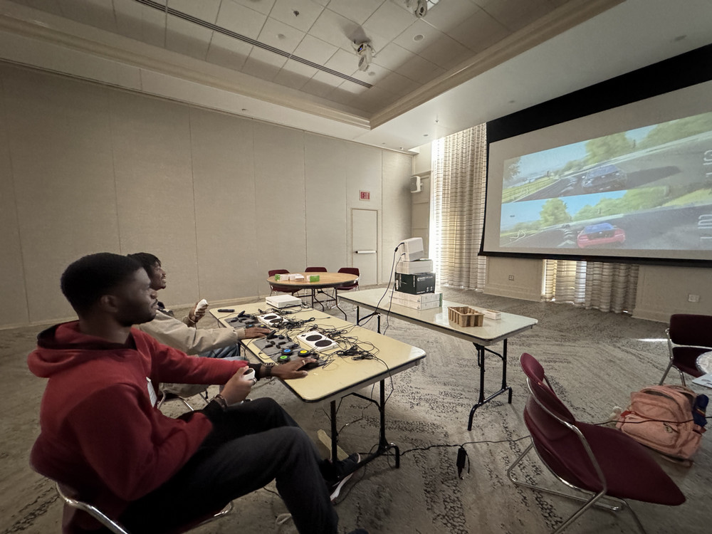 Two young men playing a racing game with adaptive controllers.
