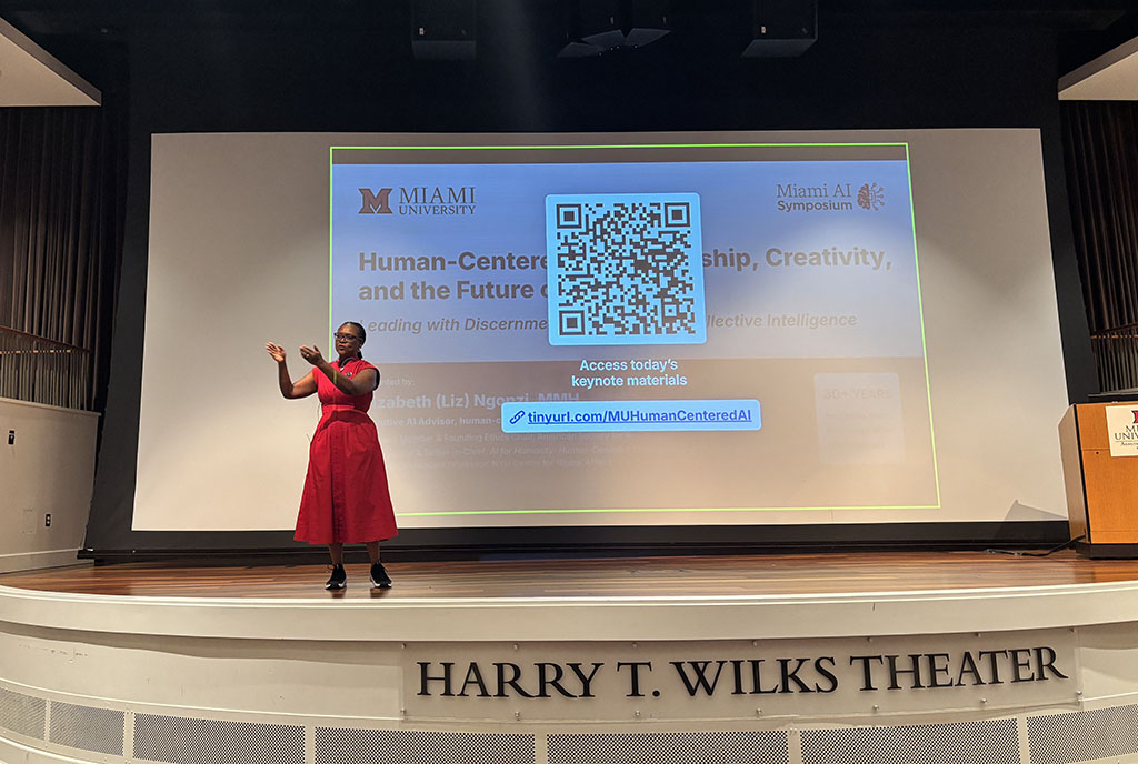 Liz Ngonzi stands on the stage at the Harry T Wilks auditorium, gesturing to the audience