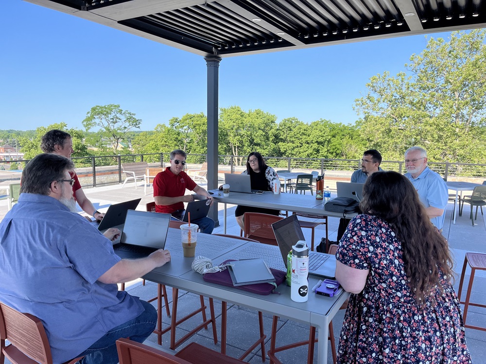 The group around a table on a sunny patio at the yearly advance in 2024
