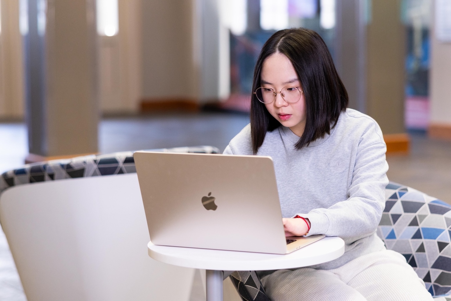 Student sitting at a table using an Apple laptop