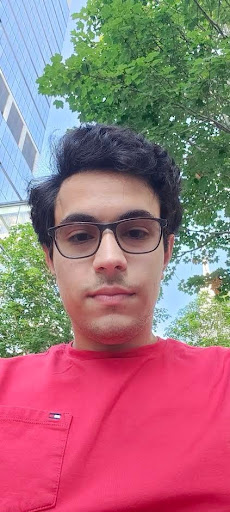 Yusuf Sevkli selfie in front of a tall building and some trees