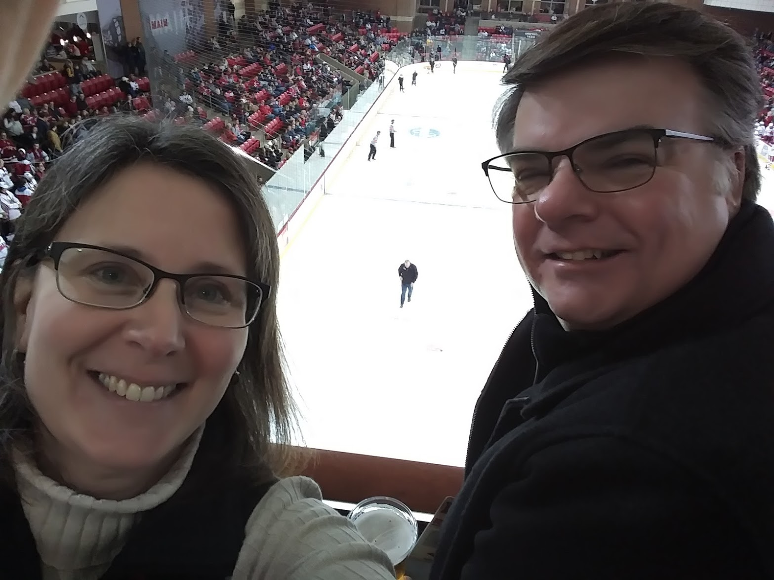 Dennis Schwind on the right and his wife, Kristen, on the left, in front of a hockey rink