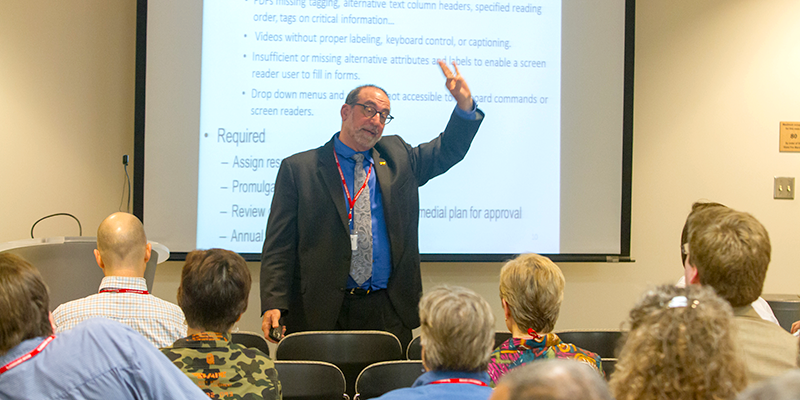 Scott Lissner delivers the keynote address in front of a PowerPoint display