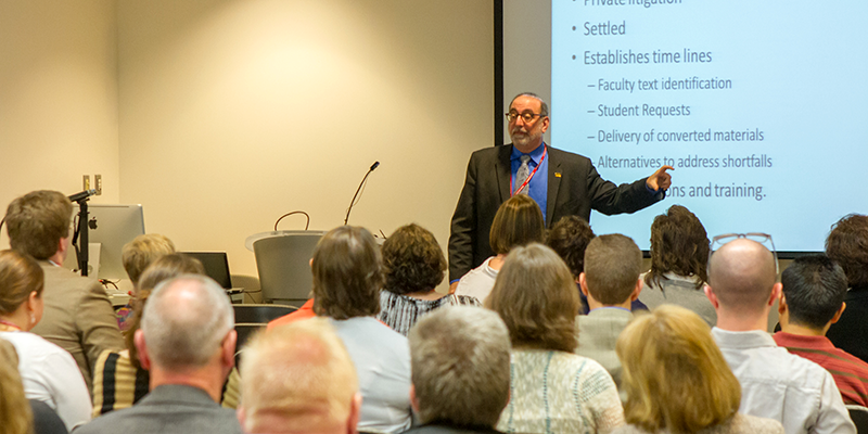 Scott Lissner gestures toward the PowerPoint presentation