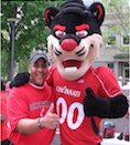 Michael Southern wearing a red Cincinnati t-shirt and hat standing the the University of Cincinnati Bearcat mascot