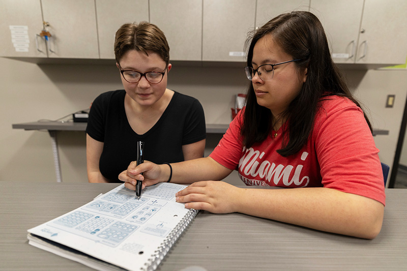 AccessMU Center intern demonstrates a smartpen to a student
