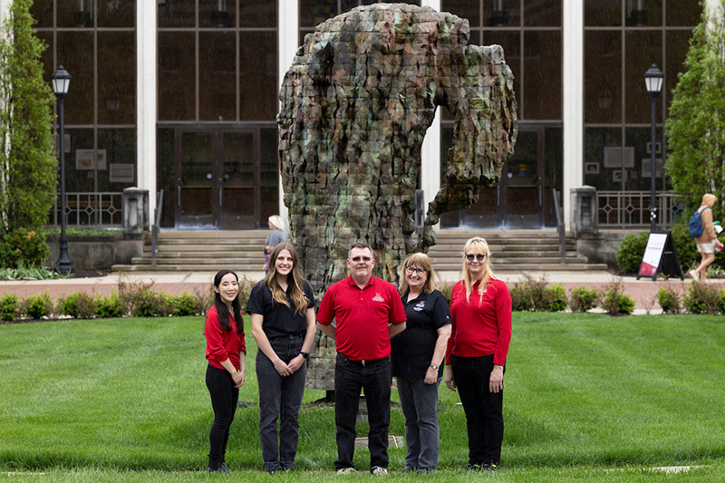 Staff pose outside Shriver Center in front of the Heart in Hand sculpture