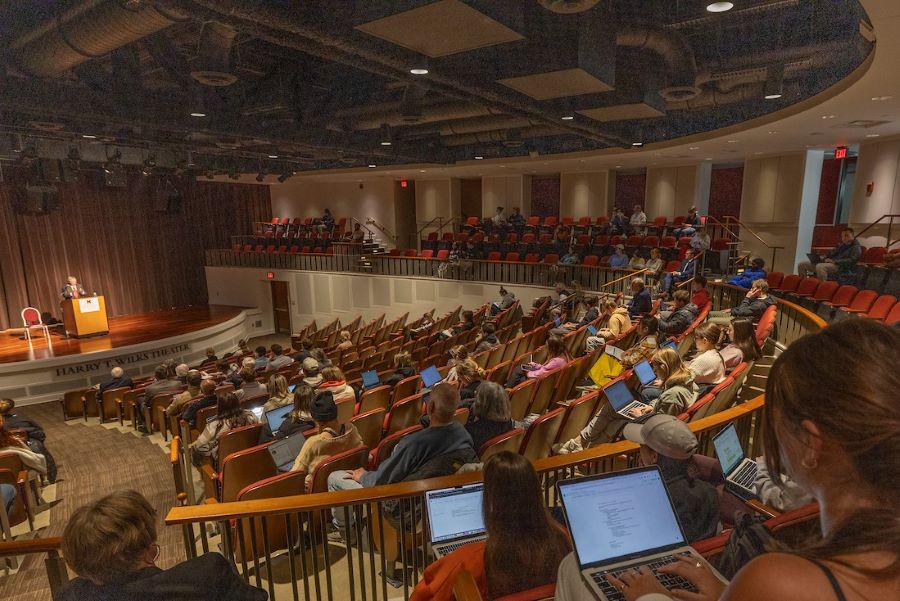 A large number of faculty and students fill the auditorium for a lecture