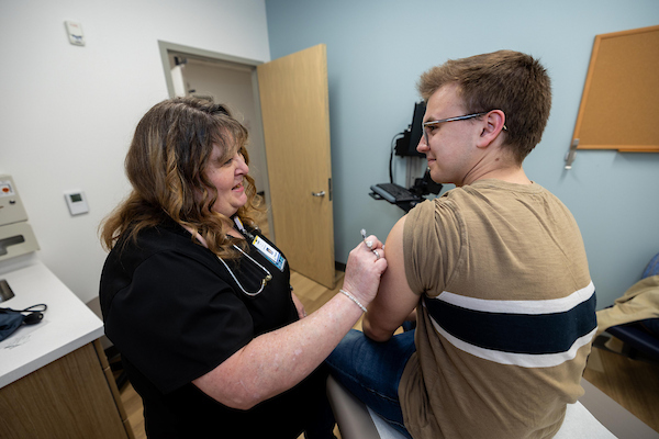 A student at the health clinic is receiving a vaccine.