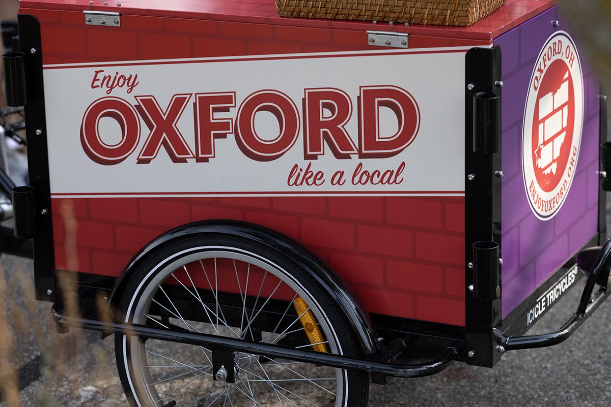 A mobile cart on wheels with a graphic on the side of the cart that reads Enjoy Oxford Like a Local.