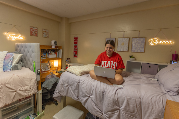 Female Student sitting on a bed in a dormroom