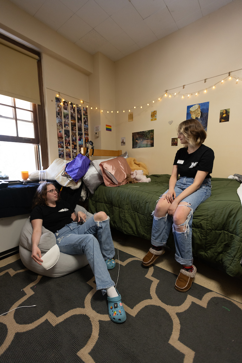 Two students talking in a dorm room after move in.