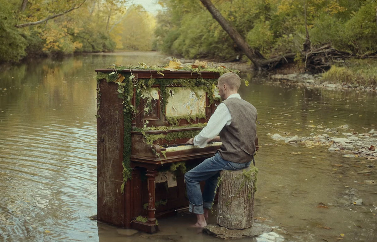 a man plays an old piano decorated with moss in four mile creek