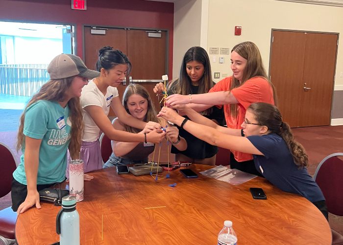 Group of 6 students building a spaghetti and marshmallow tower. 