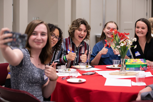5 students at a banquet table, taking a selfie. 