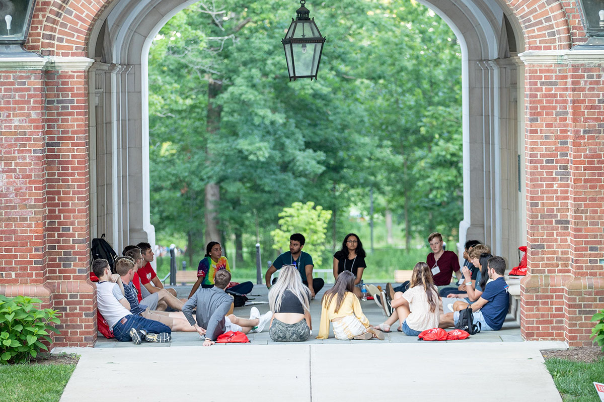 A group of new students sitting outside in a circle during orientation