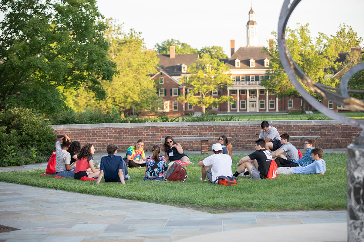 A group of students sitting on the grass for orientation