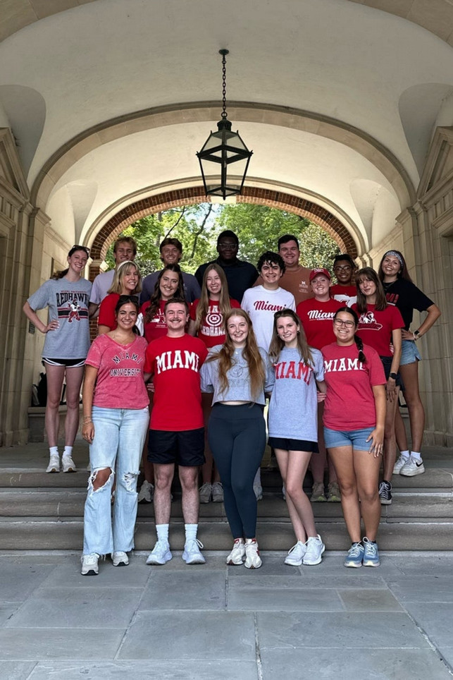 A group of students gathered on the stairs at Upham arch smiling for the camera.