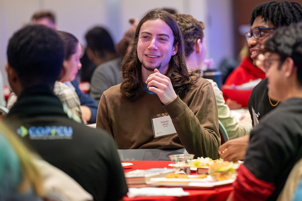 Students sitting around a table at a leadership conference during a meal. 