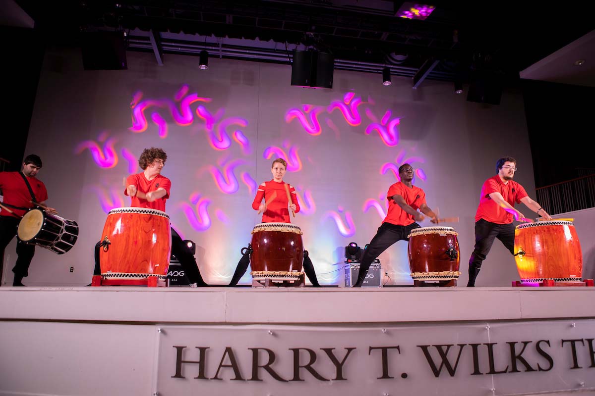 Students on stage playing various drums