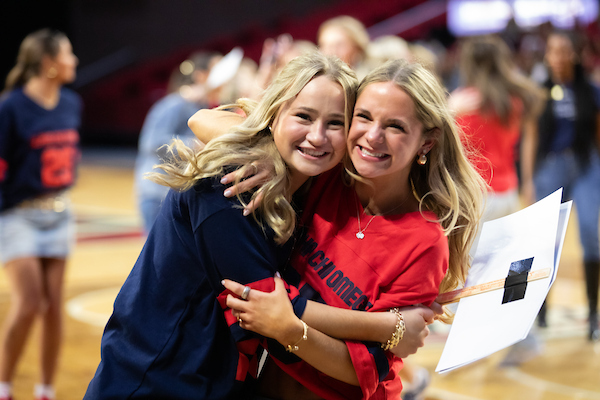 Two women hugging at Panhellenic bid day at Millett Hall.