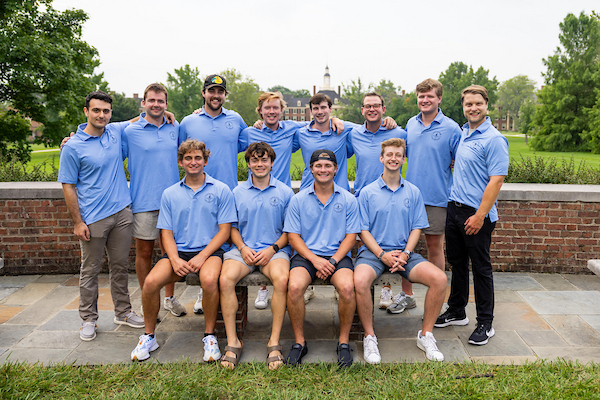 12 fraternity men standing in a line in front of south quad.