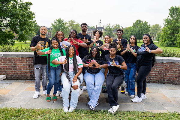 14 multicultural students where greek letters, standing in front of south quad.