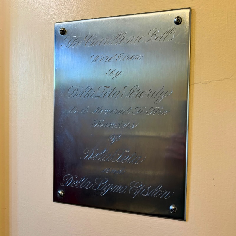 Plaque in elegant cursive font that reads The carrillonic Bells here Given By Delta Theta Sorority as a memorial to the founders of Delta Zeta and Delta Sigma Epsilon.