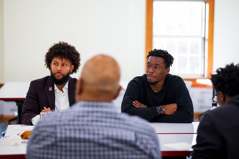 Two men sitting at a classroom table. 