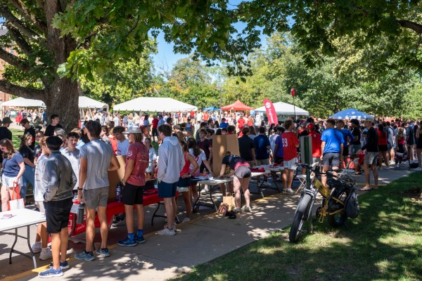 Large groups of students huddled around tables at Mega Fair.