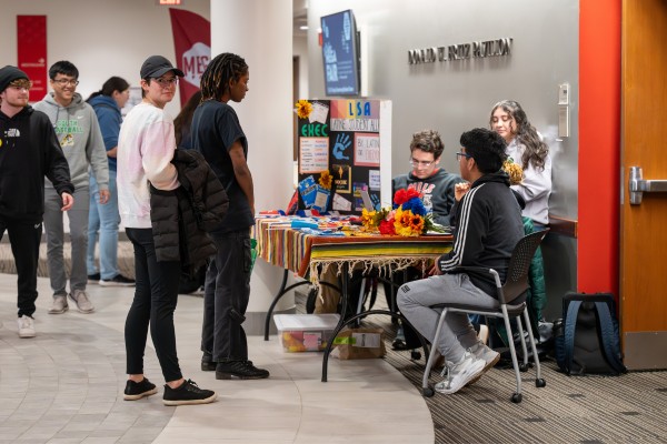 Students approaching a table outside the Student Engagement and Activities office.