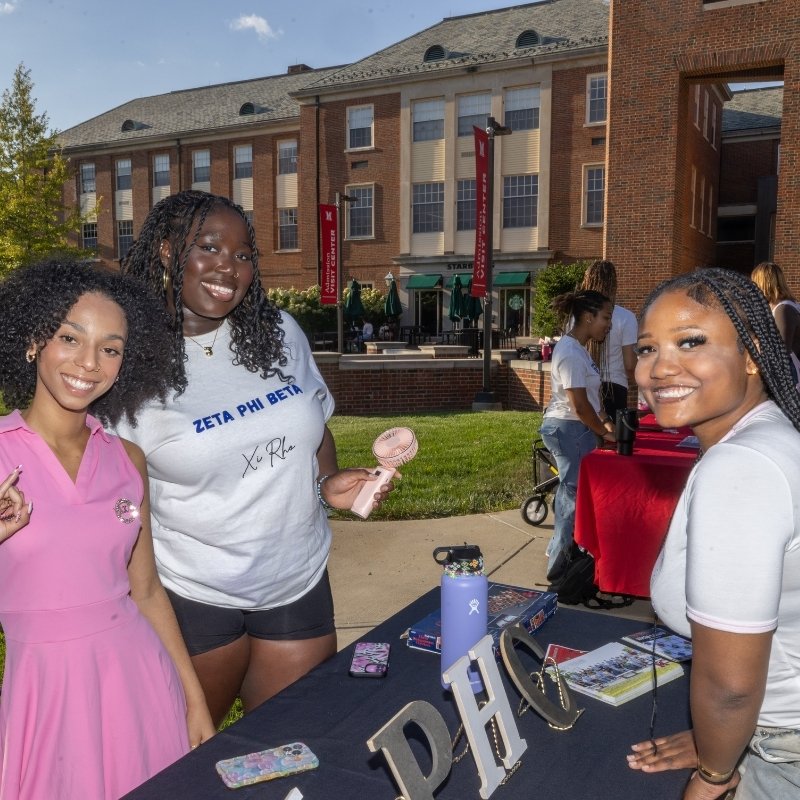 Three students at a greek organization tabling event outside Shriver.