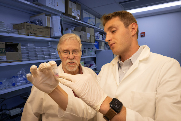 Jack Fazio working with Professor Joseph Karlin in a Microbiology lab, they are examining some vials of clear liquid