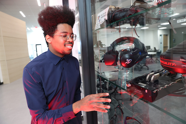 Micah Ballard showing some audio equipment in a display case