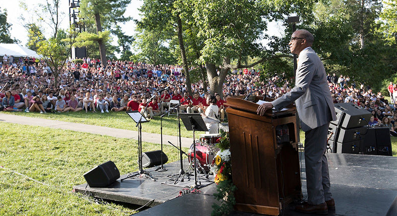 Wil Haygood stands at a podium speaking to a large crowd of students seated on the grassy hill on Western campus.
