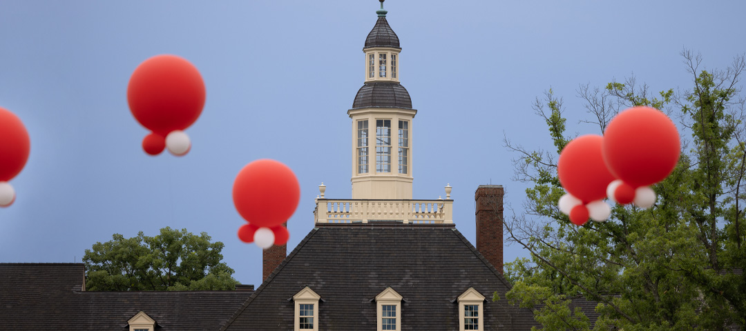 Red and white clusters of balloons floating over MacCracken Hall on Miami's Oxford campus