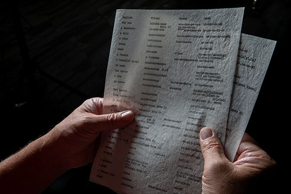 Daryl Baldwin's hands hold papers with typed Myaamia words.