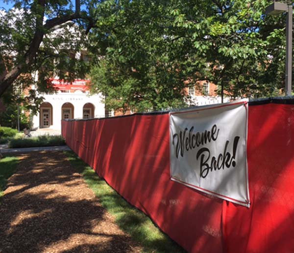 A red construction fence perpendicular to King Library, with sign Welcome Back