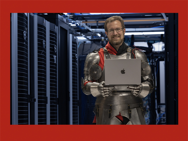 David Seidl, dressed in a suit of armor, holds a laptop inside Miami University's data center.