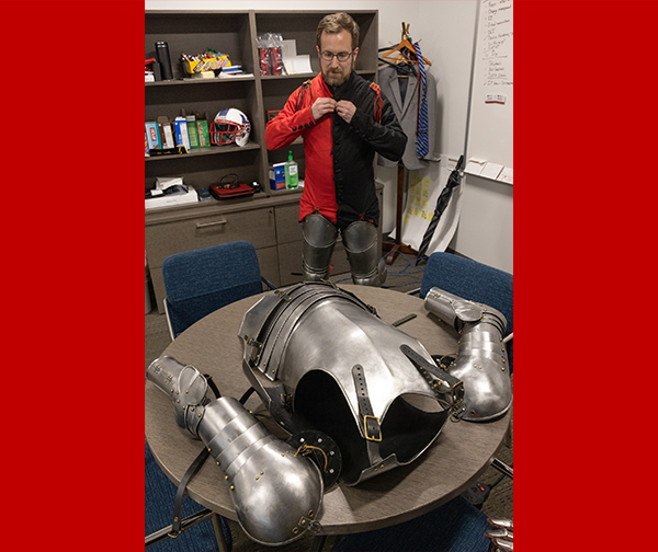 David Seidl is putting on his suit of armor in his office.