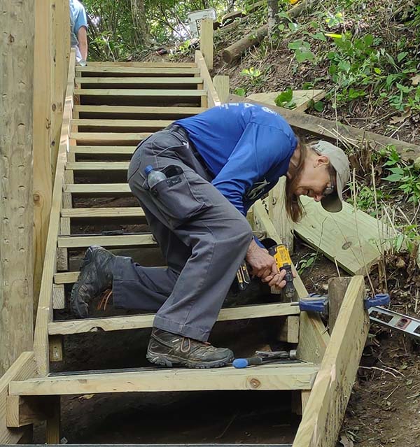 Nancy Feakes works on a set of wooden steps on a steep trail