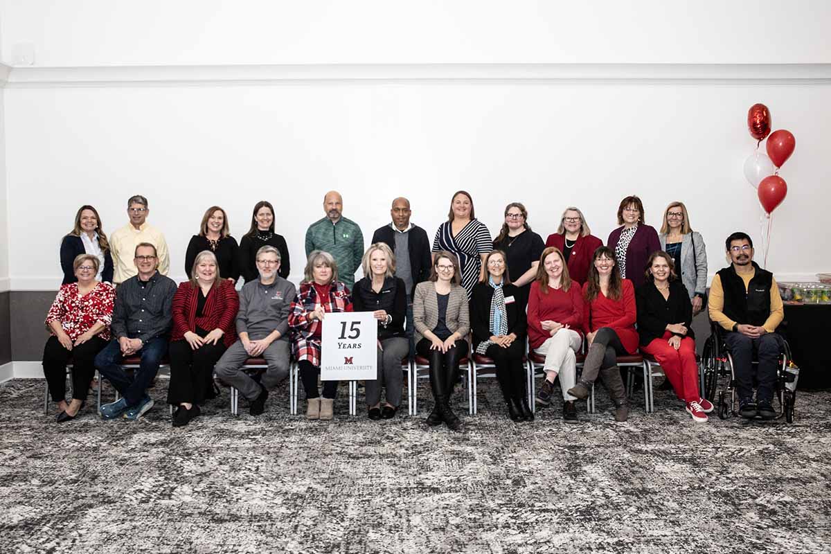 A large group of Miami employees pose with a "15 years of service" sign in the Dolibois room