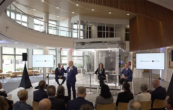 four people speak to an audience in front of the IBM One quantum computer at the Cleveland Clinic