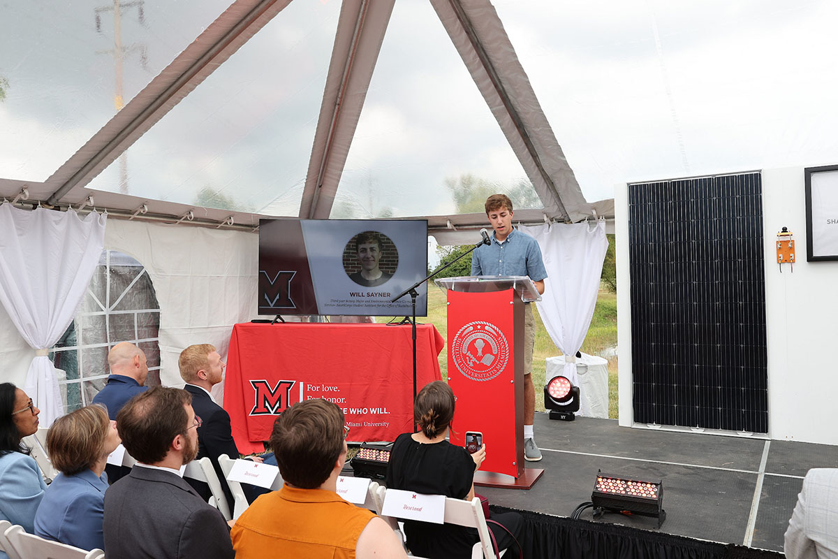 Will Sayner speaks to an audience in an event tent 