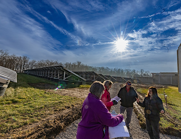 solar arrays, pond, sun. 3 people