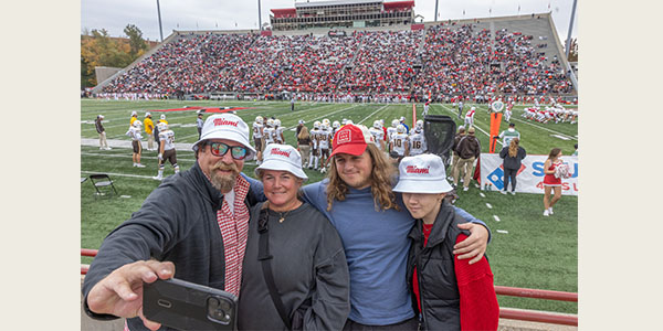 Four people take a photo in the stands of Yager Stadium during Family Weekend 2025