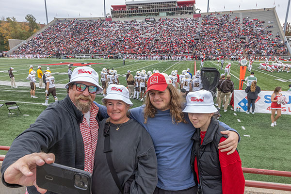 Four people take a photo in the stands of Yager Stadium during Family Weekend 2025