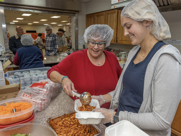 nancy parkinson works with student to prepare monday meals